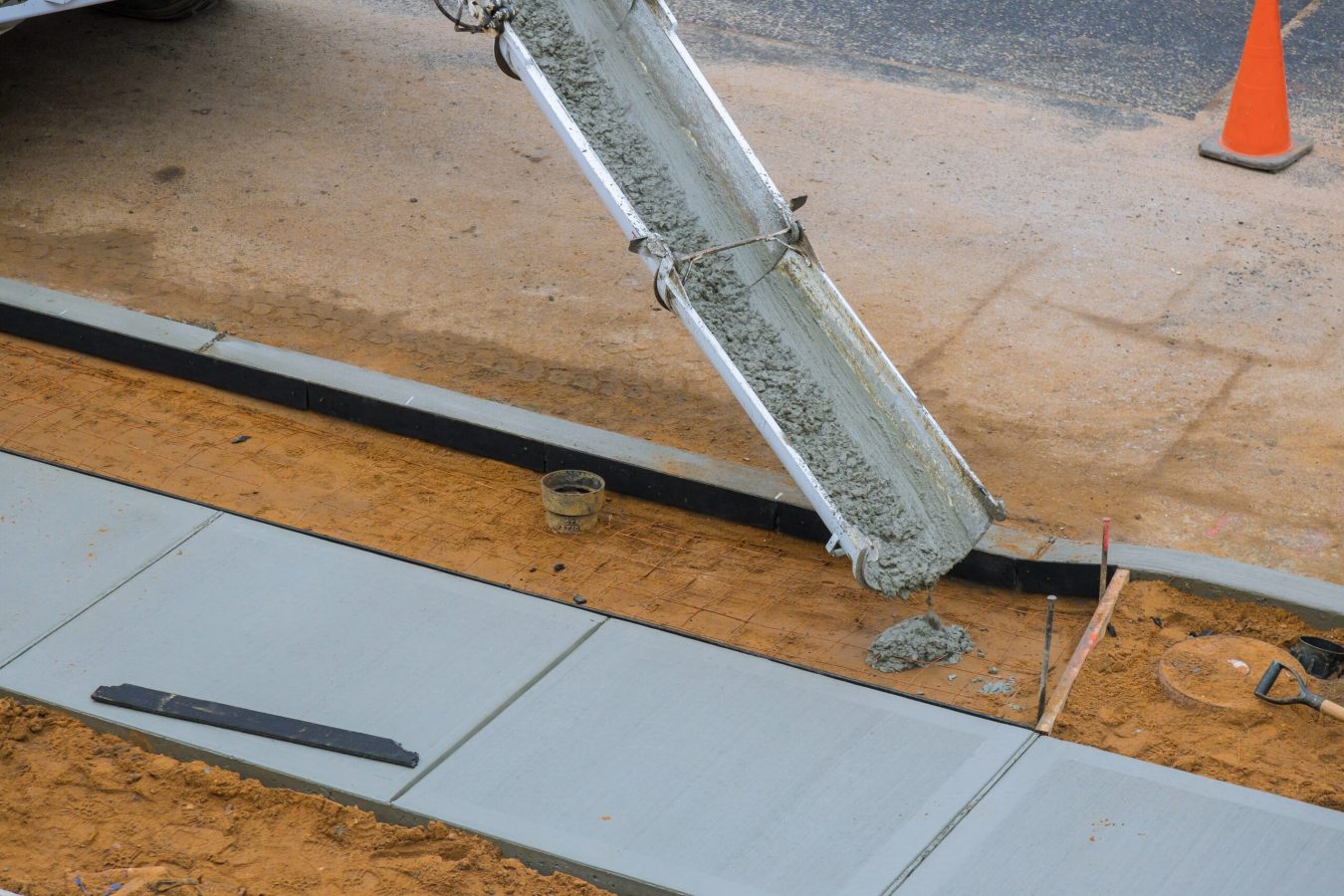 Concrete being poured from a mixer truck into a concrete with sidewalk